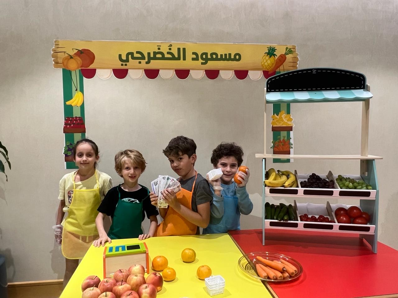 Children running a role-play grocery stall with Arabic signage